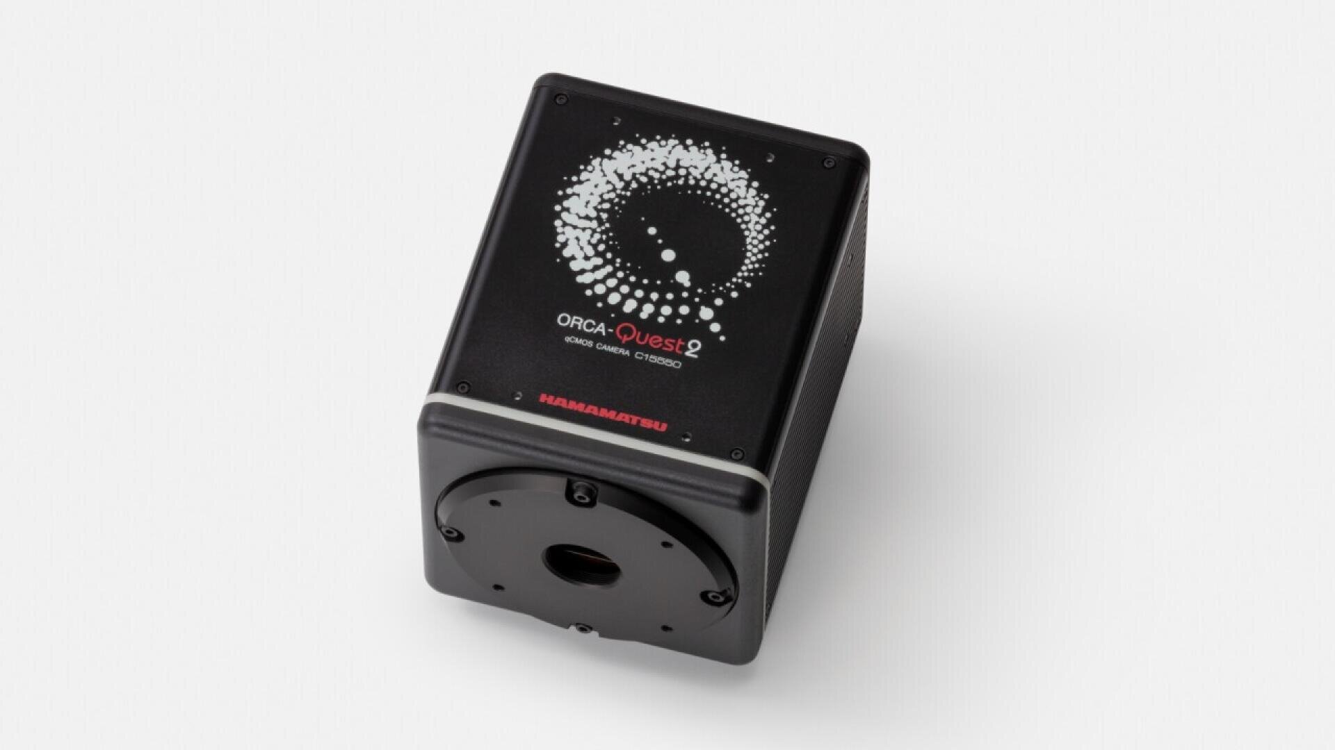 Eine schwarze rechteckige wissenschaftliche Kamera mit der Aufschrift „ORCA-Quest qCMOS Camera“ und einem kreisförmigen Punktmuster auf der Oberseite, hergestellt von Hamamatsu, abgebildet vor einem schlichten weißen Hintergrund.